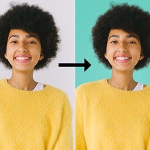 May include: A person with curly dark brown hair is smiling and wearing a yellow fuzzy sweater. The person is standing in front of a white background.