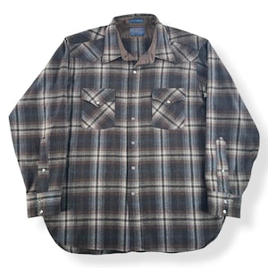 May include: A long-sleeved plaid shirt in shades of gray, brown, and white. The shirt features two chest pockets with silver snap closures, a brown corduroy collar, and silver snap cuffs. The shirt is laid flat on a white surface.