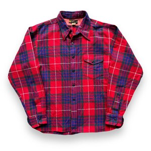 May include: Red and blue plaid flannel shirt with a button-up front and a single chest pocket.