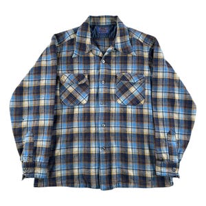 May include: A blue, tan, and navy plaid button-down shirt. The long-sleeved shirt has two front pockets and a classic collar. The fabric has a soft, textured appearance. The shirt is buttoned up and appears to be in good condition.