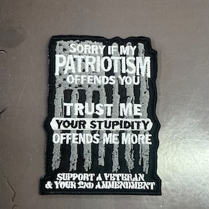 May include: A rectangular black and white embroidered patch. The text reads "SORRY IF MY PATRIOTISM OFFENDS YOU TRUST ME YOUR STUPIDITY OFFENDS ME MORE SUPPORT A VETERAN & YOUR 2ND AMENDMENT". The patch has a black border and a distressed flag design.