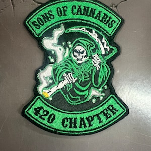 May include: Embroidered patch with the text "SONS OF CANNABIS" and "420 CHAPTER" in green on a black background. The patch features a green Grim Reaper smoking a joint, with white smoke rising.