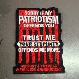 May include: A rectangular black patch with white text that reads "SORRY IF MY PATRIOTISM OFFENDS YOU TRUST ME YOUR STUPIDITY OFFENDS ME MORE SUPPORT A VETERAN & YOUR 2ND AMENDMENT". The text is in a distressed style with red vertical stripes.