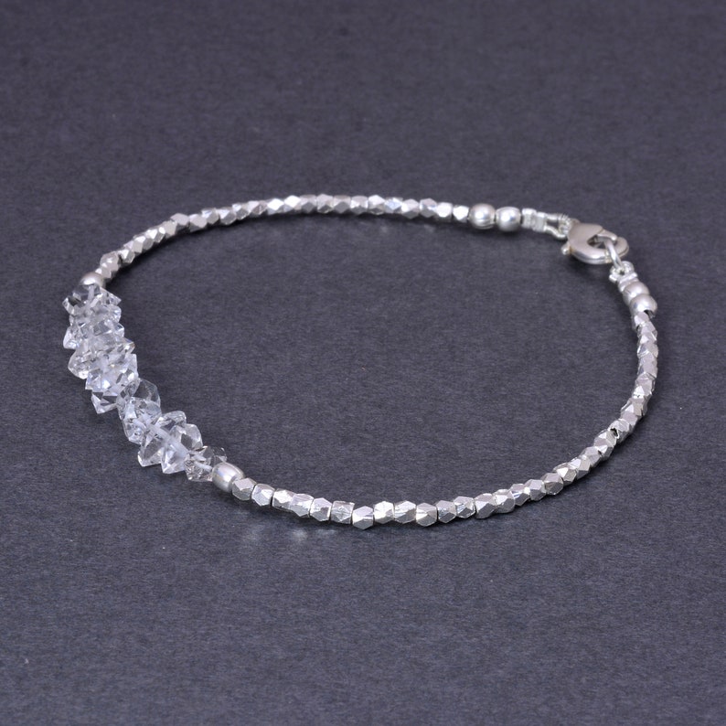 K&ouml;nnte beinhalten: Ein silbernes Armband mit einer Reihe von klaren Kristallperlen und einem silbernen Verschluss.