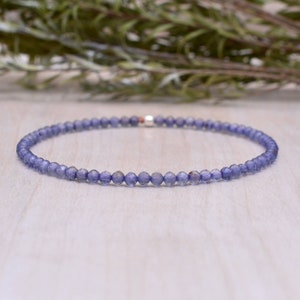 May include: A delicate bracelet made with small, light blue gemstone beads. The bracelet is strung on a silver chain and has a simple, elegant design.