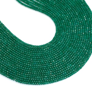 May include: A close-up view of a strand of faceted, emerald green beads. The beads are small, uniform in size, and strung together, creating a flowing, curved shape against a white background. The beads have a slight sparkle.