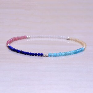 May include: A delicate bracelet featuring a gradient of gemstone beads. The bracelet has pink, blue and white beads, creating a colourful and eye-catching design.