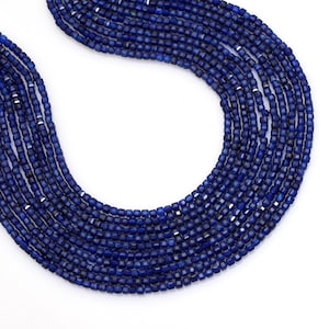 May include: A collection of dark blue, square-cut gemstone beads strung together. The beads are uniform in size and shape, creating a smooth, flowing appearance. The necklace is displayed against a white background.