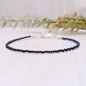 Może przedstawiać: Delikatna bransoletka z niebieskich koralików szafirowych z srebrnym zapięciem. Bransoletka wykonana jest z małych, okrągłych koralików i idealnie nadaje się do codziennego noszenia.