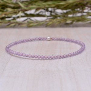 May include: A delicate amethyst gemstone bracelet with a silver clasp. The bracelet is made of small, round beads and is a light purple colour.