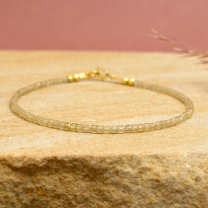 May include: A fine bracelet composed of small, pale green beads. It has gold-coloured clasps and connectors. The beads are uniform in size, forming a delicate and elegant piece of jewellery.