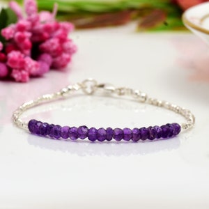 May include: A delicate silver bracelet with a row of small, faceted amethyst beads. The bracelet has a simple clasp closure.