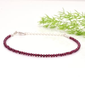 Può includere: Un delicato braccialetto a catena d'argento con piccole perle di granato rosso scuro. Il braccialetto è semplice ed elegante, perfetto per l'uso quotidiano.