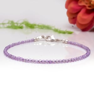 May include: A delicate amethyst gemstone bracelet with a silver clasp. The bracelet is made of small, round beads and is perfect for everyday wear.