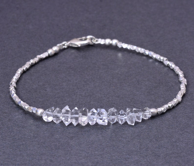 K&ouml;nnte beinhalten: Ein silbernes Armband mit einer Reihe von klaren, facettierten Kristallen und einem silbernen Verschluss.