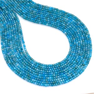 May include: Strands of small, square-cut, light blue gemstones. The beads are strung together, forming a flowing, curved shape. The gemstones have a slightly translucent quality, with variations in color.