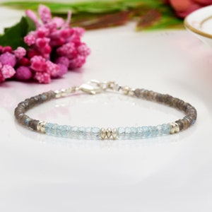 May include: A delicate bracelet featuring alternating beads of light blue aquamarine and gray labradorite, separated by silver beads.