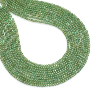 May include: Strands of small, faceted green beads. The beads are strung together on a green thread, creating a flowing, organic shape. The beads have a slightly translucent quality, and the overall effect is one of delicate beauty.