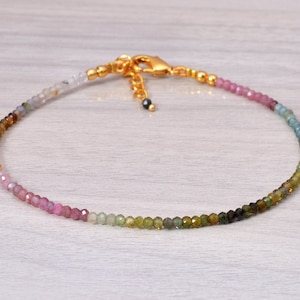 Peut inclure: Un bracelet délicat composé de petites pierres précieuses facettées dans des tons de rose, vert et bleu. Le bracelet a un fermoir doré.