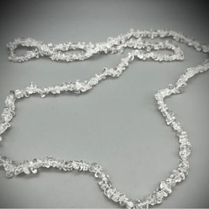 Op de afbeelding: Een lange streng van heldere kwartskristal kralen die aan elkaar geregen zijn om een ​​ketting te vormen.