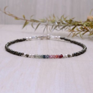 Può includere: Un braccialetto delicato con un arcobaleno di minuscole pietre preziose e perline d'argento. Il braccialetto è realizzato con perline di pirite.