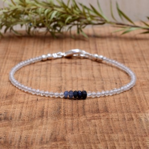 Pode incluir: Um delicado bracelete feito com contas de quartzo transparente e uma fileira de contas de safira azul. O bracelete tem um fecho de prata.