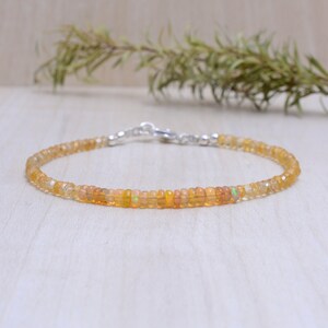 Peut inclure: Un bracelet délicat composé de petites perles rondes d'opale orange et jaune. Le bracelet est doté d'un fermoir argenté.