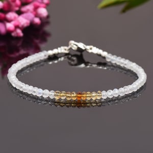 Pode incluir: Um delicado bracelete feito com contas de pedra da lua branca e citrino. O bracelete tem um fecho de prata.