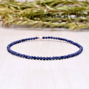 May include: A delicate blue gemstone bracelet made with small, faceted beads. The bracelet is strung on a silver chain and has a simple, elegant design.