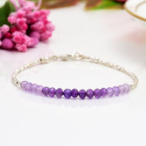 May include: A silver bracelet with a gradient of amethyst beads, ranging from light to dark purple.