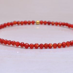 Pode incluir: Um bracelete de pedra de cornalina vermelha com pequenas contas facetadas.