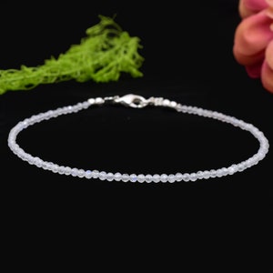 May include: A delicate silver chain bracelet with small, clear moonstone beads.