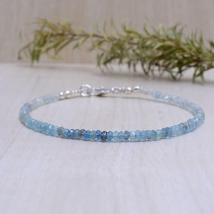 May include: A delicate silver chain bracelet with small, light blue aquamarine beads. The bracelet is simple and elegant, perfect for everyday wear.