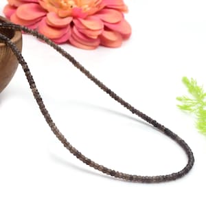 Peut inclure: Un collier de perles de pierres précieuses gris foncé, enfilées sur un fil fin. Les perles sont petites et facettées, ce qui leur donne un léger éclat.