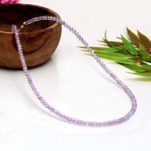 Könnte beinhalten: Eine zarte Halskette aus kleinen, facettierten Amethystperlen. Die Perlen sind helllila und auf einer silbernen Kette aufgefädelt.
