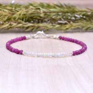 May include: A delicate bracelet with a two-tone design. The bracelet is made with small, faceted pink and white beads. The beads are strung on a silver chain with a lobster clasp.