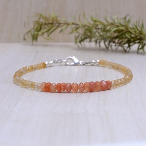 Puede incluir: Un delicado brazalete hecho con pequeñas cuentas redondas de piedra de sol naranja y amarilla. El brazalete tiene un cierre de plata.