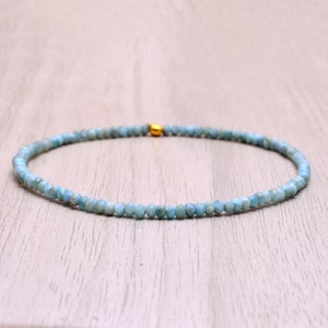 Op de afbeelding: Een delicate ketting van blauwe edelstenen met een gouden sluiting. De ketting is gemaakt van kleine, ronde kralen en is perfect voor dagelijks gebruik.