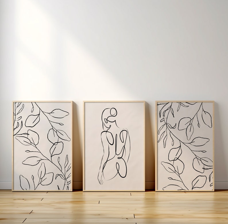 May include: Three minimalist line art prints in wooden frames. The prints feature a single line drawing of a person, and two prints feature a single line drawing of leaves.