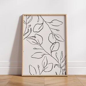 May include: A framed black and white line drawing of leaves and branches on a light pink background.