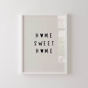 Könnte beinhalten: Weißer gerahmter Druck mit dem Text "HOME SWEET HOME" in schwarzen Buchstaben mit einem Herzsymbol zwischen den Wörtern "HOME".