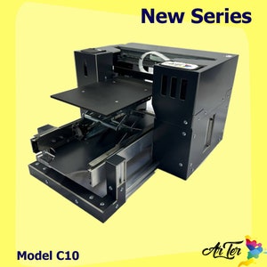 May include: A black and silver 3D printer with a black platform and a clear plastic tube. The printer is labelled "New Series" and "Model C10".