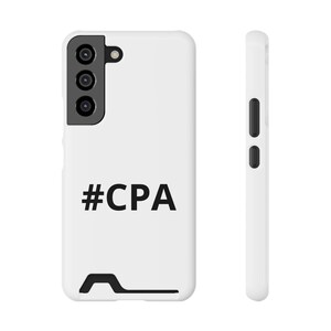 Könnte beinhalten: Eine weiße Smartphone-Hülle mit dem schwarzen Text #CPA auf der Rückseite. Die Hülle verfügt über einen schwarzen Kameraausschnitt mit drei kreisförmigen Linsenöffnungen und einem Blitz sowie einen schwarzen rechteckigen Schlitz am unteren Rand.