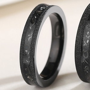 May include: Two black rings with a textured finish and a silver-colored design on the edge.