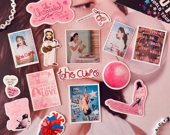 May include: A collection of assorted stickers featuring various designs, including photographic portraits, a red anatomical heart, a pink circular graphic, and text-based art with phrases like The Unraveled Tour and You Seem Pretty Sad For A Girl So In Love.