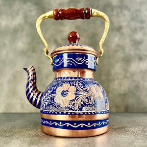 May include: A blue and gold copper teapot with a floral design. The teapot has a wooden handle and a gold spout.