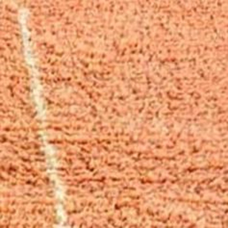 Pu&ograve; includere: Primo piano di una superficie strutturata marrone-rossastra con una linea bianca diagonale. La superficie sembra essere un campo sportivo, forse per il tennis o un gioco simile.