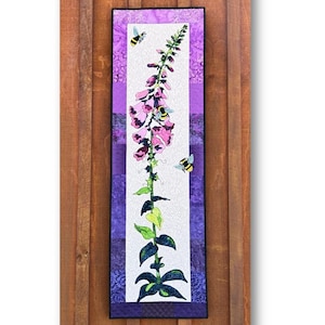 May include: A purple and white quilt block with a foxglove flower and bees. The block is titled "Bee-U-tiful Foxglove" and is part of a larger quilt titled "Hare They Are!" The block measures 15 inches by 48 and a half inches.