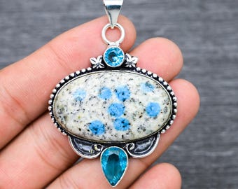 Könnte beinhalten: Ovaler Anhänger mit einem blau-weiß gefleckten Stein, der in Silber gefasst ist. Der Anhänger ist mit zwei kleineren blauen Steinen verziert.