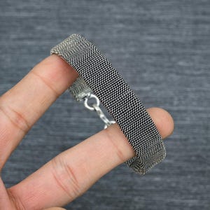 Peut inclure: Un bracelet en argent avec un motif de chaîne tissée. Le bracelet est composé de petits maillons interconnectés qui créent un motif texturé et géométrique.